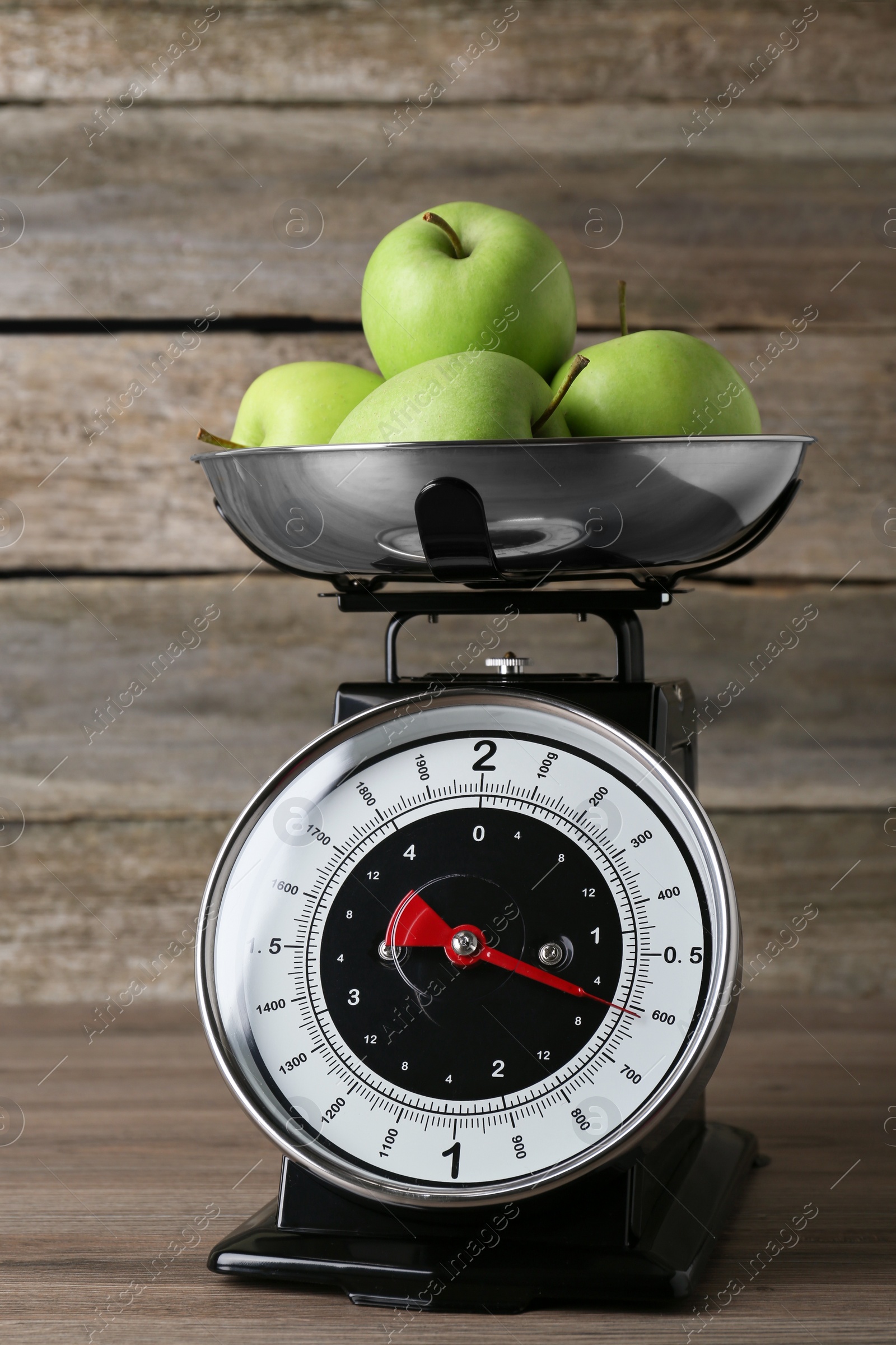 Photo of Kitchen scale with green apples on wooden table