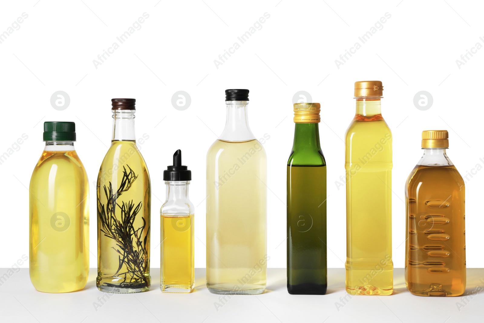 Photo of Bottles of different cooking oils on white background