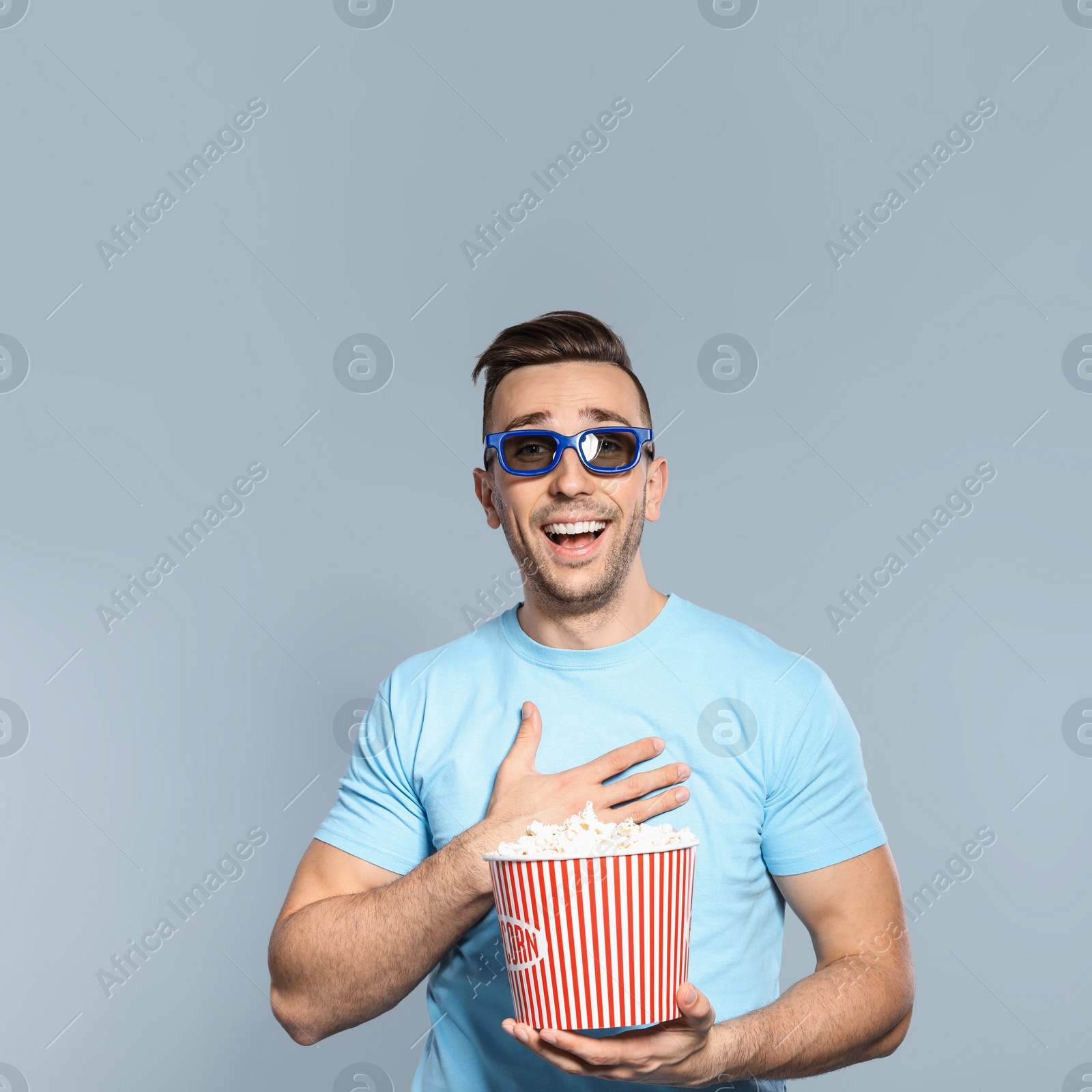 Photo of Man with 3D glasses and popcorn during cinema show on grey background