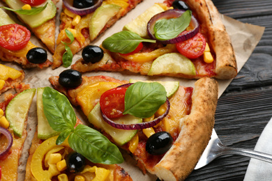 Photo of Delicious vegetable pizza on black wooden table, closeup