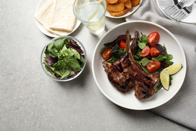 Photo of Delicious grilled ribs served on light grey table, flat lay