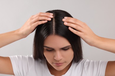 Photo of Woman examining her hair and scalp on grey background, closeup