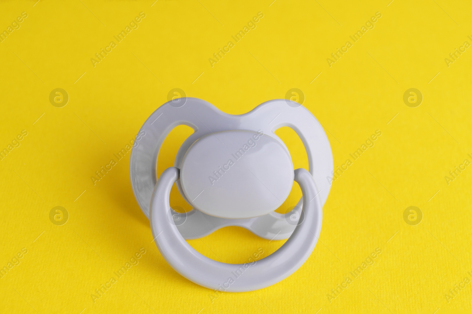 Photo of New cute baby pacifier on yellow background