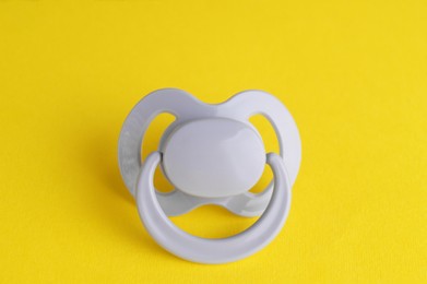 New cute baby pacifier on yellow background