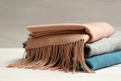 Photo of Stack of cashmere clothes on wooden table, closeup