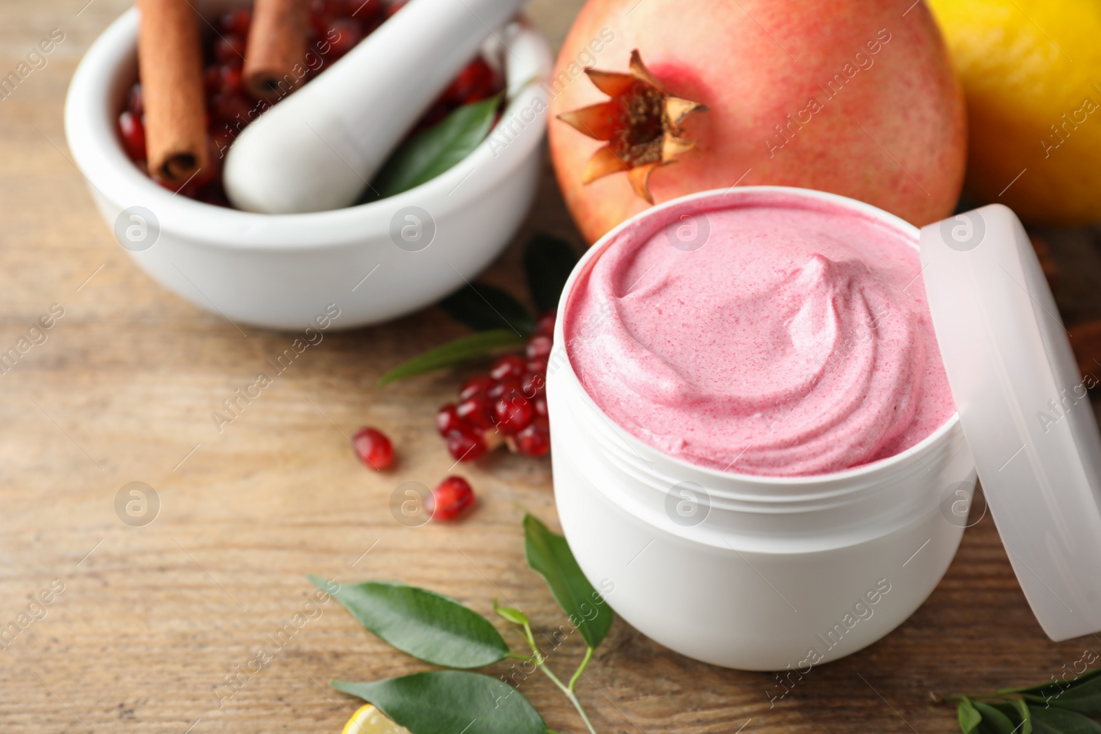 Photo of Natural homemade mask, pomegranate and ingredients on wooden table, closeup