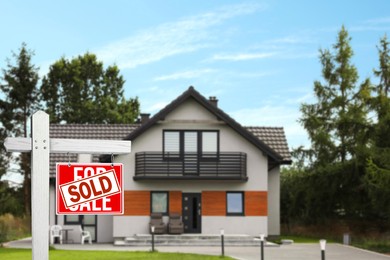 Image of Red sale sign with Sold sticker near house