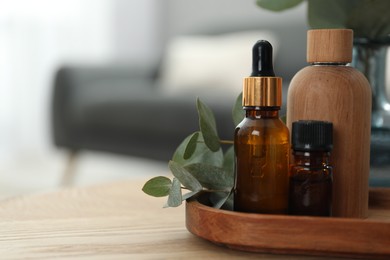 Aromatherapy. Bottles of essential oil and eucalyptus leaves on wooden table, space for text