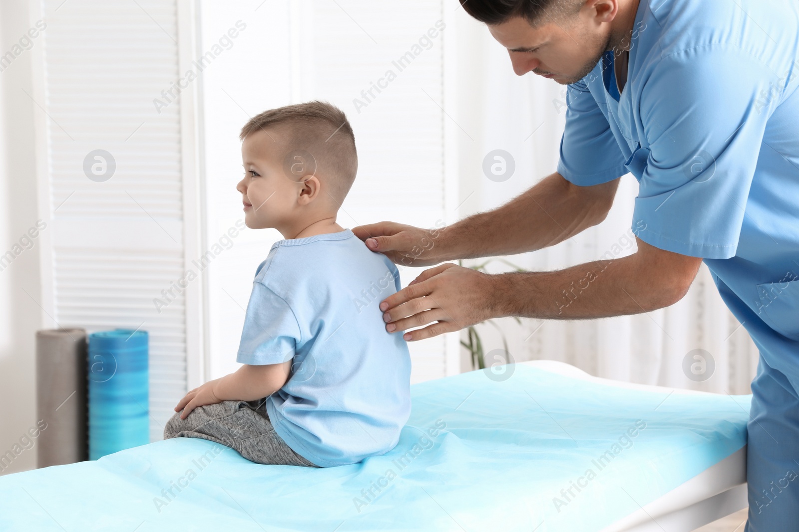 Photo of Orthopedist examining child's back in clinic. Scoliosis treatment