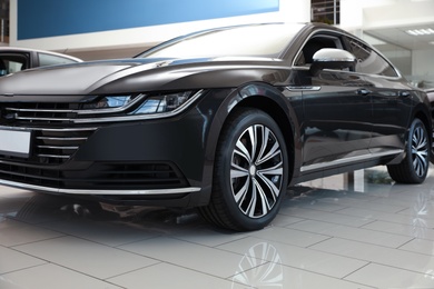 Photo of New luxury black car in modern auto dealership, closeup