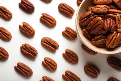 Delicious fresh pecan nuts and bowl on white background, flat lay