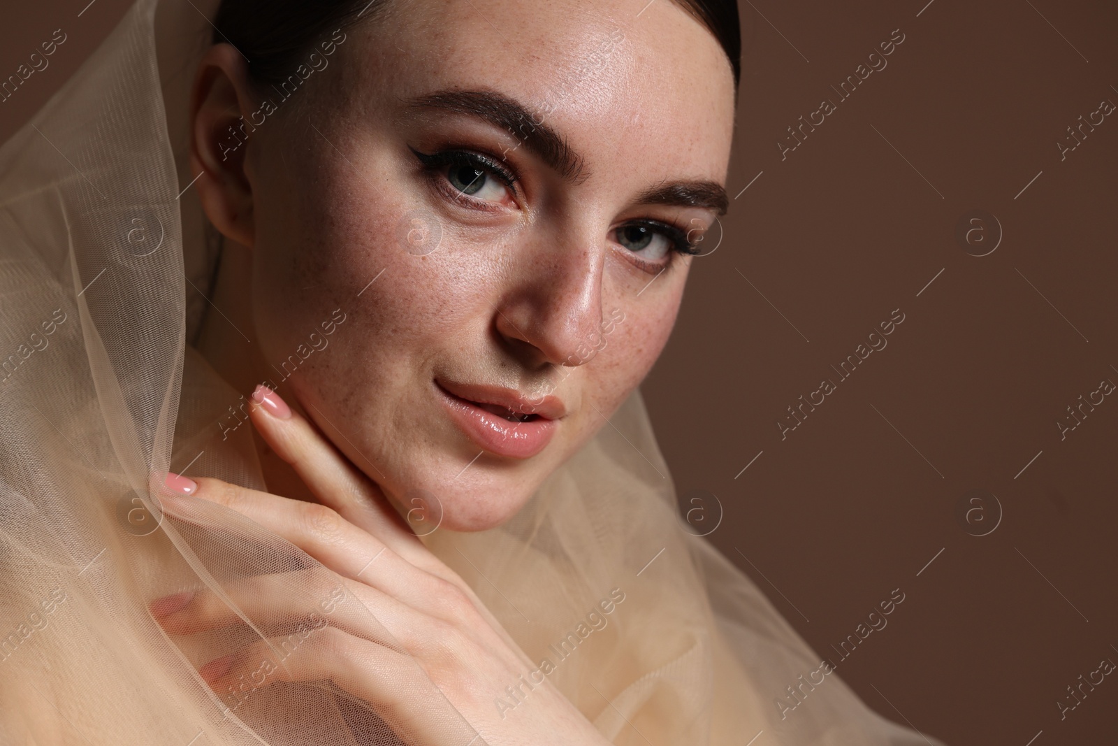 Photo of Fashionable portrait of beautiful woman with fake freckles on brown background, closeup