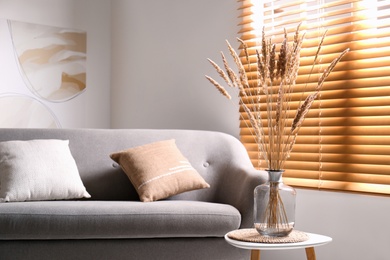 Vase with decorative dried plants on table in living room. Interior design