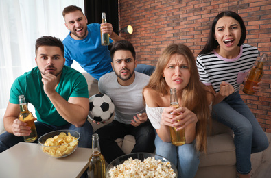 Group of friends watching football at home