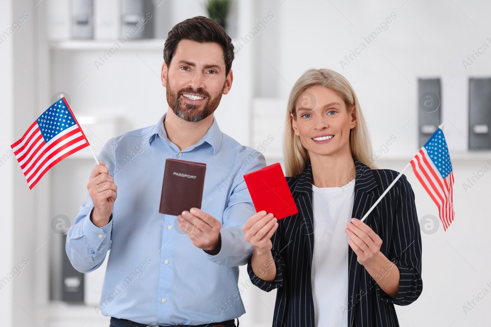 Photo of Immigration. Happy couple with passports and American flags indoors