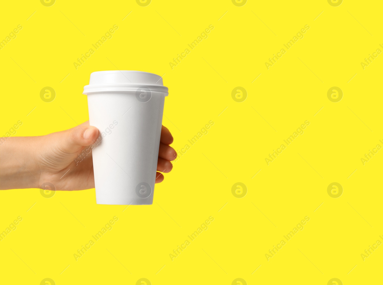 Photo of Woman holding takeaway paper coffee cup on yellow background, closeup. Space for text