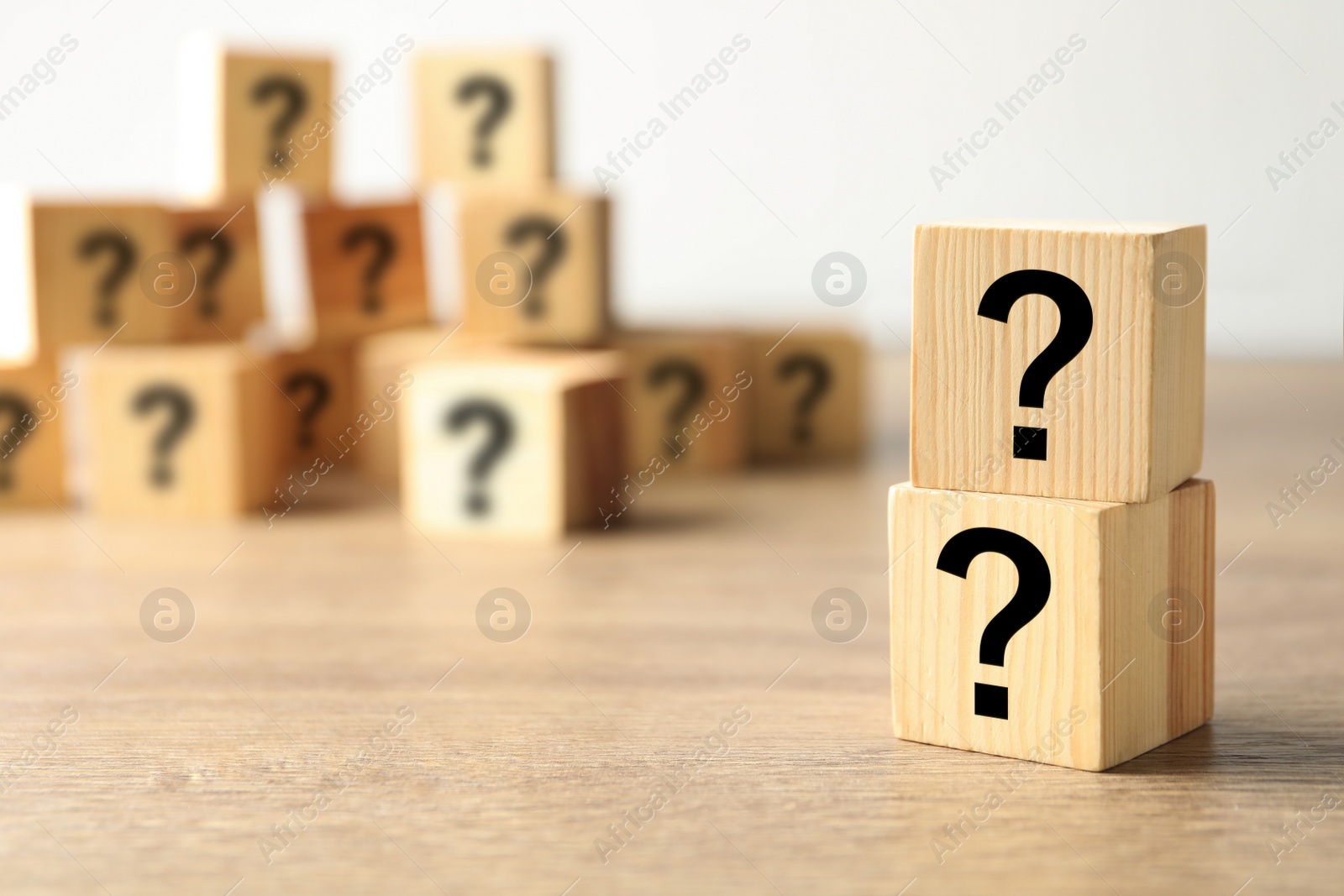 Photo of Cubes with question marks on wooden background. Space for text