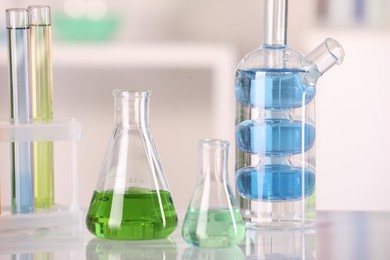 Photo of Laboratory analysis. Different glassware with liquids on white table against blurred background