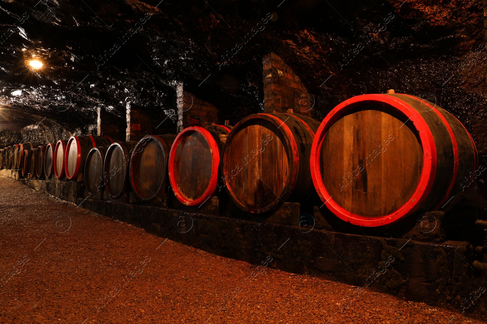 Photo of Many wooden barrels with alcohol drinks in cellar