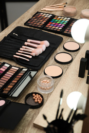 Photo of Set of different professional makeup products on wooden table in studio