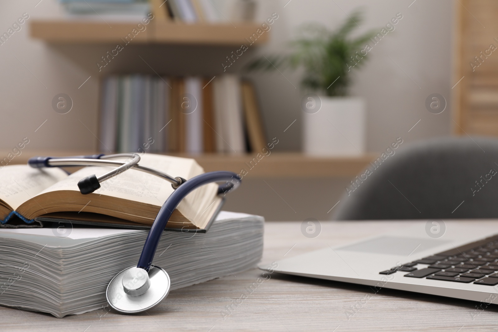 Photo of Book, stethoscope, laptop and stack of documents on table indoors, space for text. Medical education