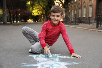 Child drawing cat with chalk on asphalt