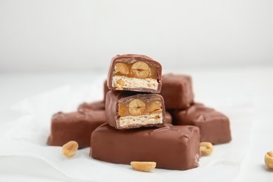 Photo of Chocolate bars with caramel, nuts and nougat on white table, closeup