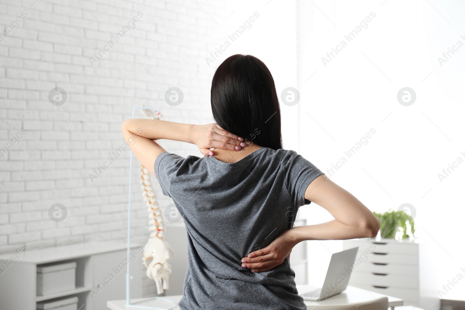 Photo of Woman suffering from pain in back at clinic. Visiting orthopedist