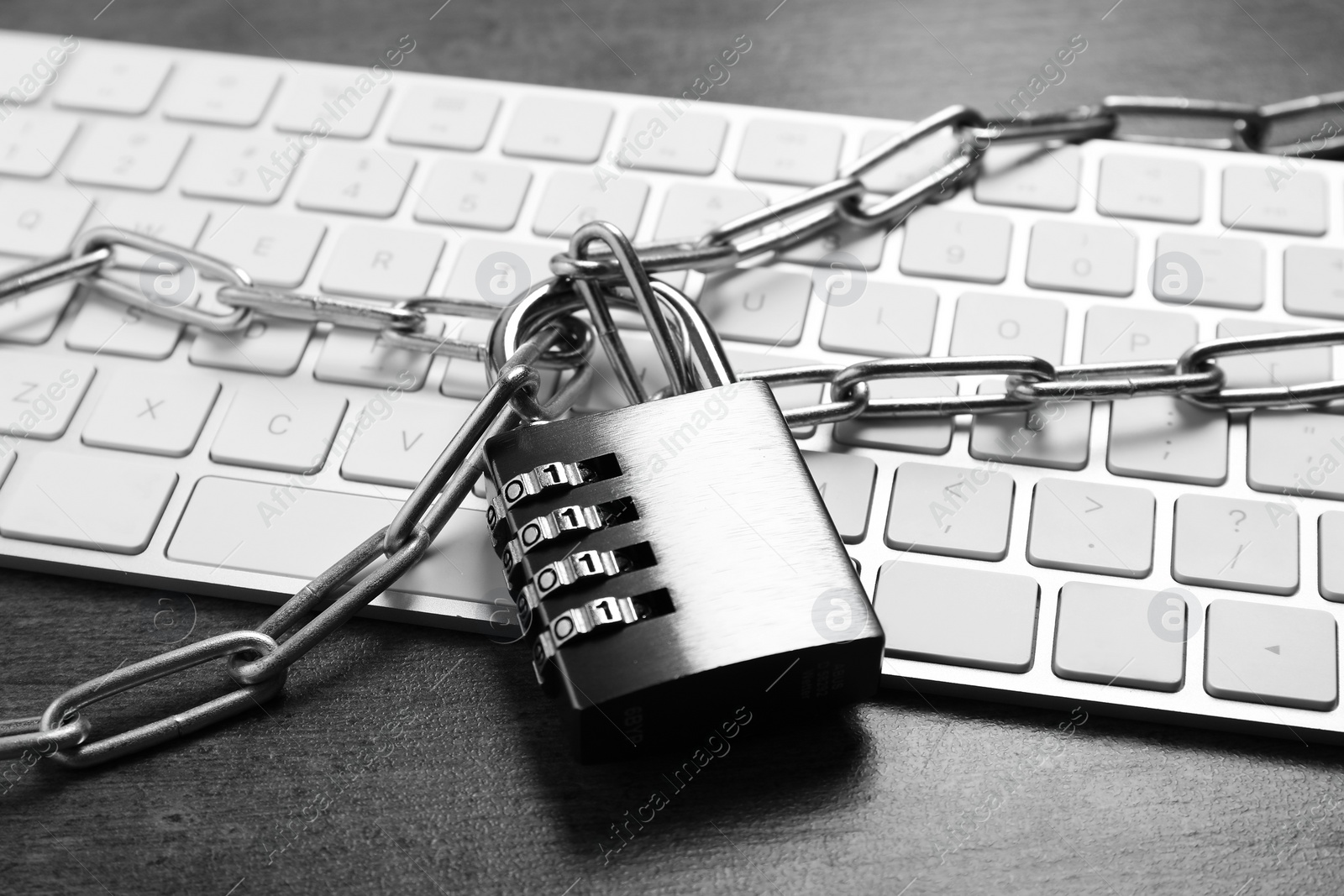 Photo of Cyber security. Metal combination padlock with chain and keyboard on grey table, closeup