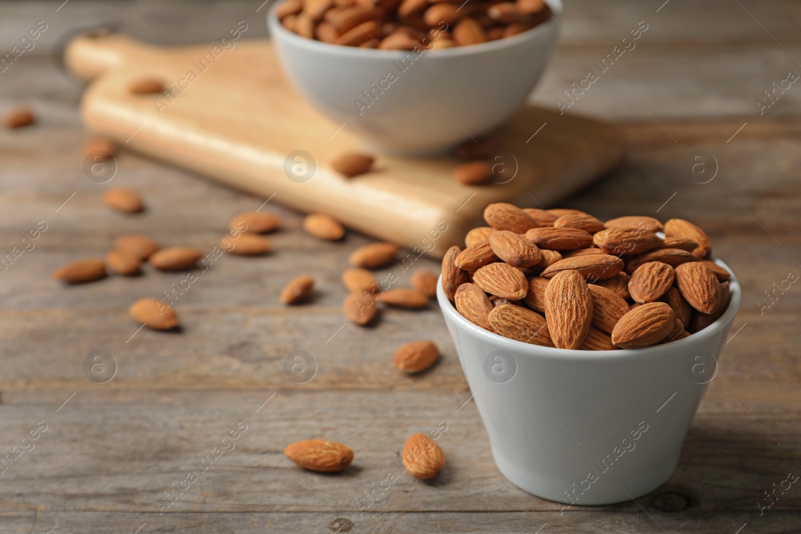 Photo of Tasty organic almond nuts in bowl on table. Space for text