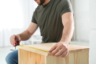 Photo of Young working man using measure tape at home, closeup