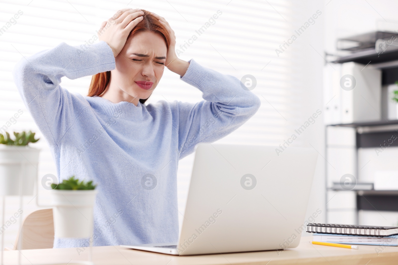 Photo of Woman suffering from headache at workplace in office