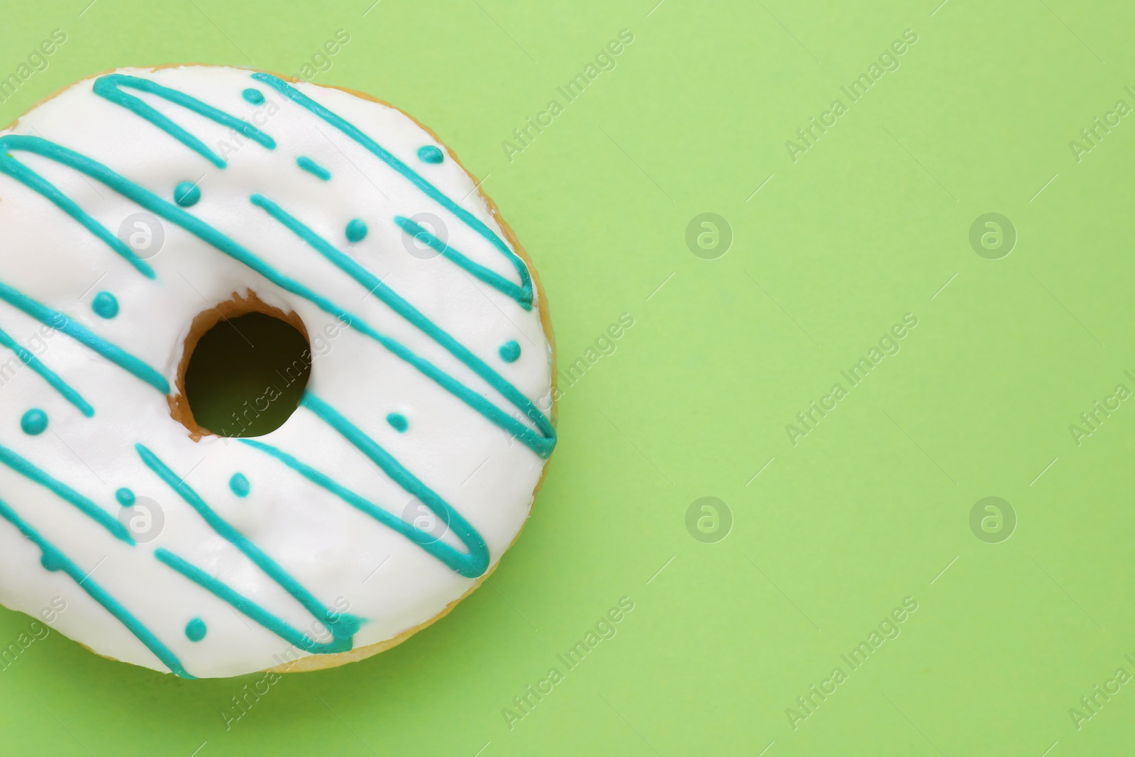 Photo of Tasty glazed donut on green background, top view. Space for text
