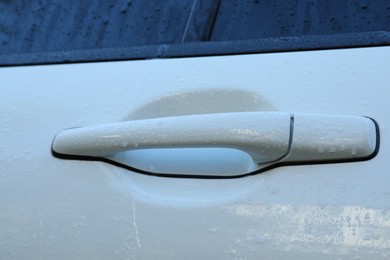 Closeup view of car door handle with water drops