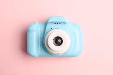 Photo of Light blue toy camera on pink background, top view. Future photographer