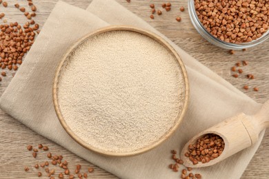 Photo of Bowl with buckwheat flour and seeds on wooden table, flat lay