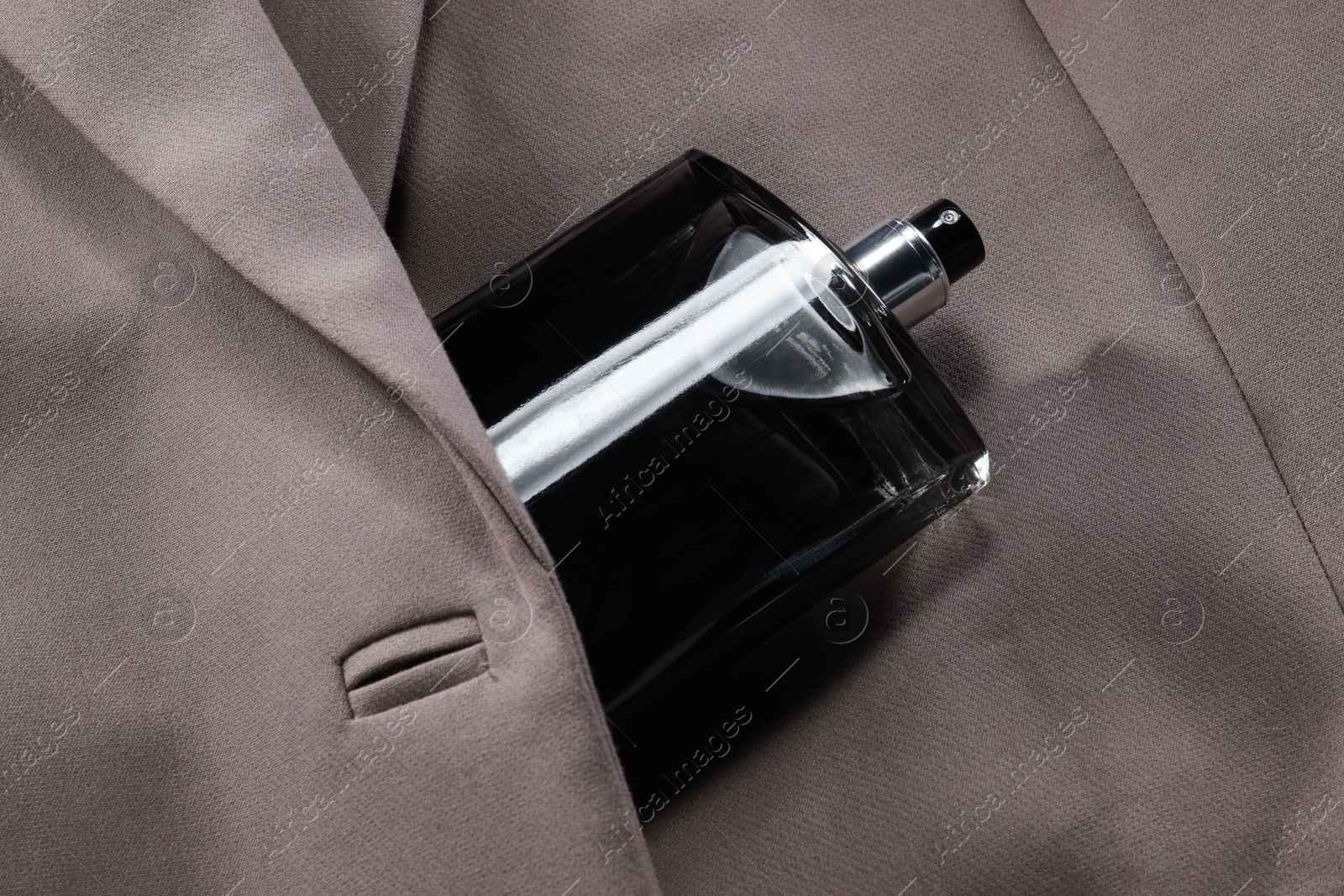 Photo of Luxury men's perfume in bottle on beige jacket, above view