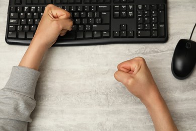 Photo of Angry man with clenched fists at table during work, top view