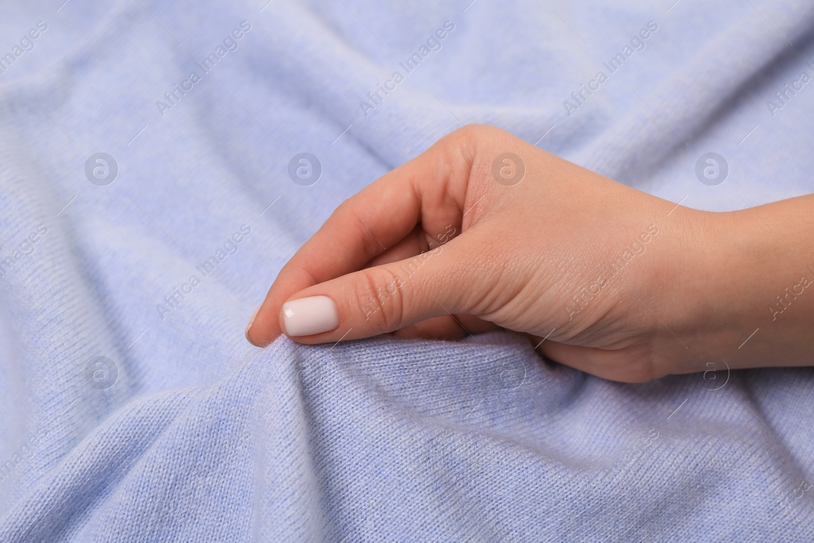 Photo of Woman touching soft light blue fabric, closeup