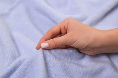 Woman touching soft light blue fabric, closeup