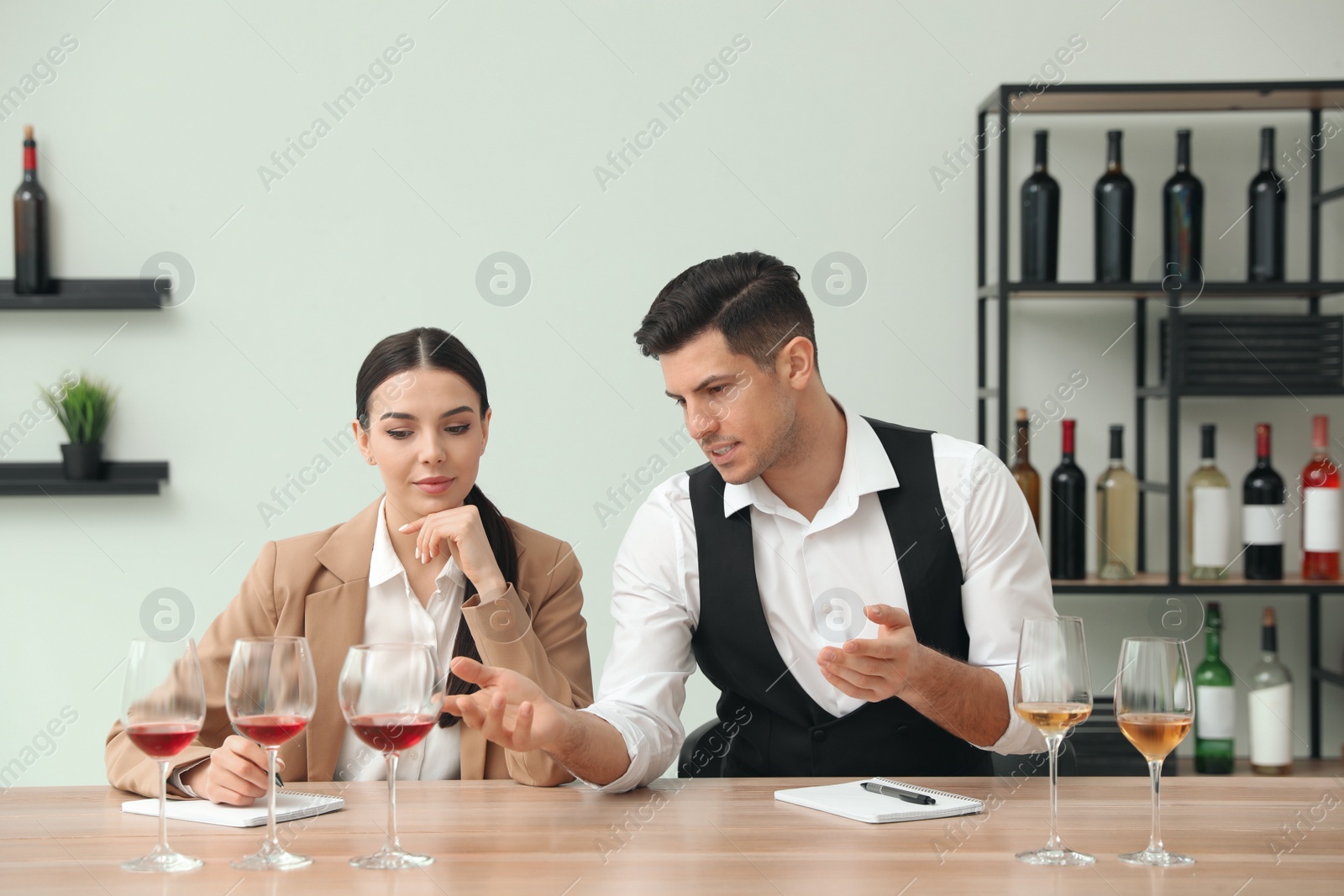 Photo of Sommeliers tasting different sorts of wine at table indoors