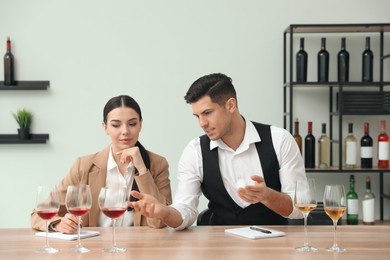 Photo of Sommeliers tasting different sorts of wine at table indoors
