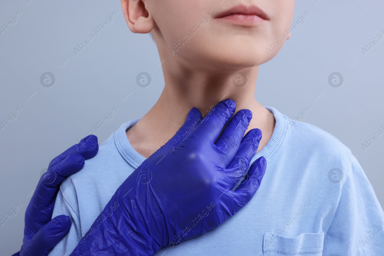 Photo of Endocrinologist examining boy's thyroid gland on light grey background, closeup