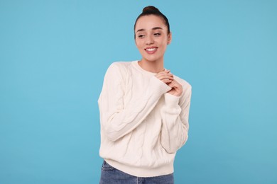 Beautiful young woman in stylish warm sweater on light blue background