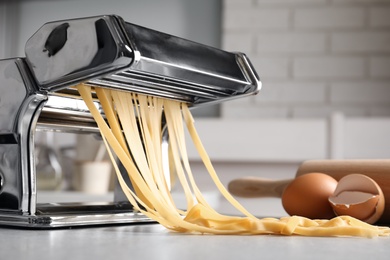 Photo of Pasta maker with dough on kitchen table