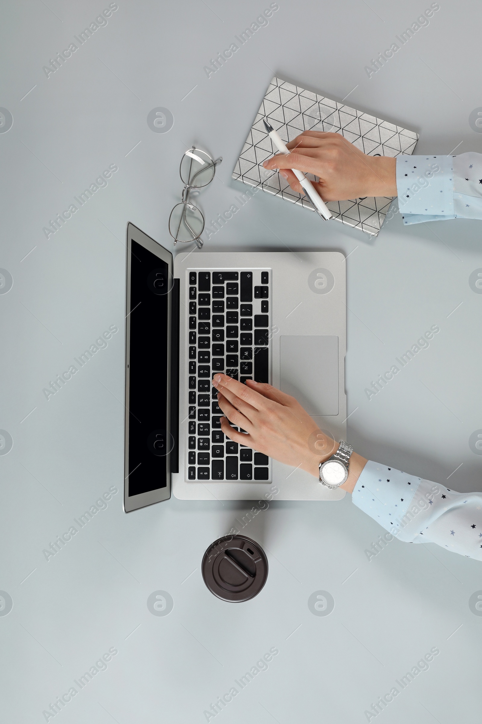 Photo of Woman working with modern laptop at table, top view