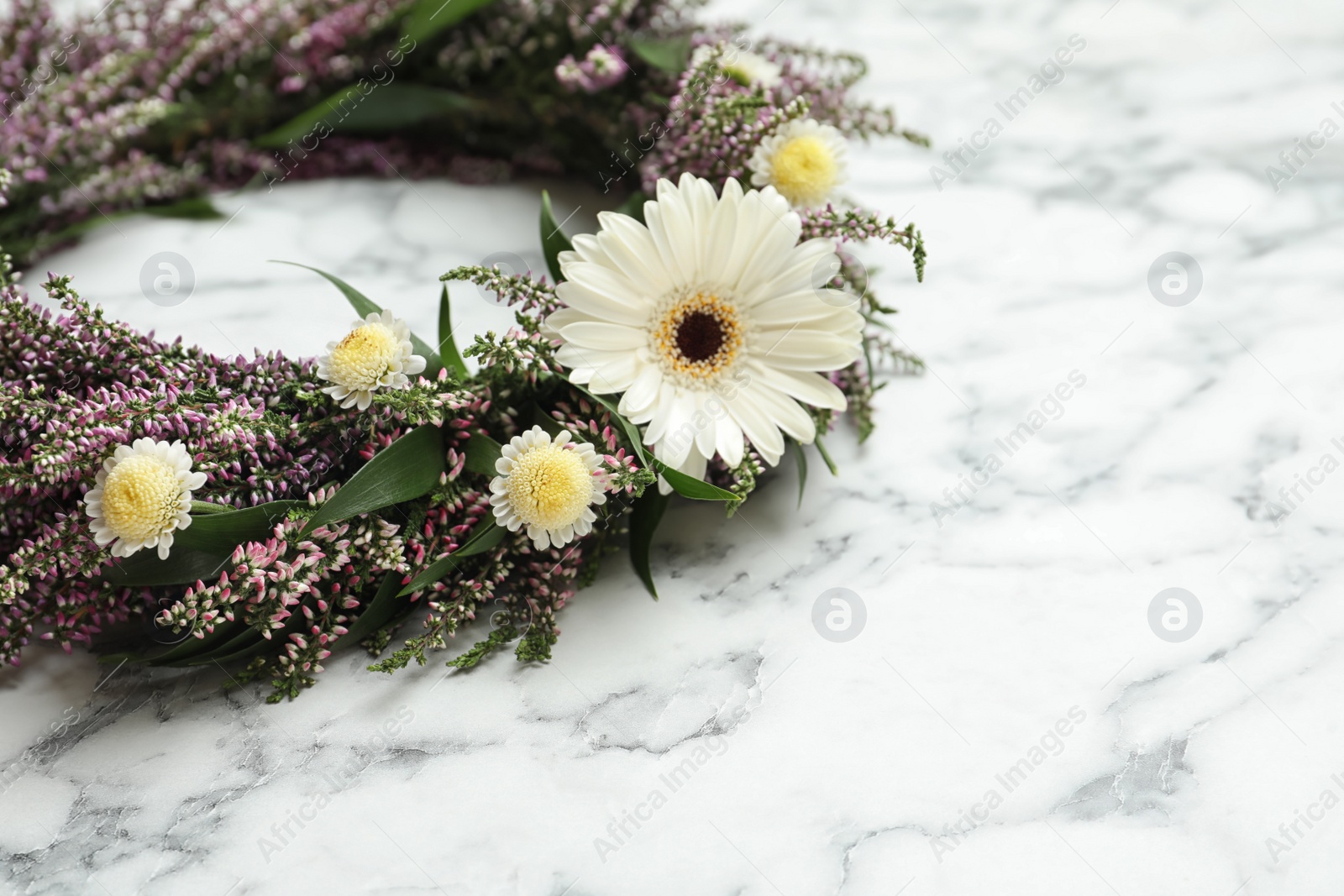 Photo of Beautiful autumnal wreath with heather flowers on white marble background, closeup. Space for text