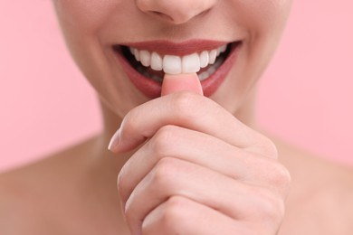 Photo of Woman with beautiful lips biting her finger on pink background, closeup