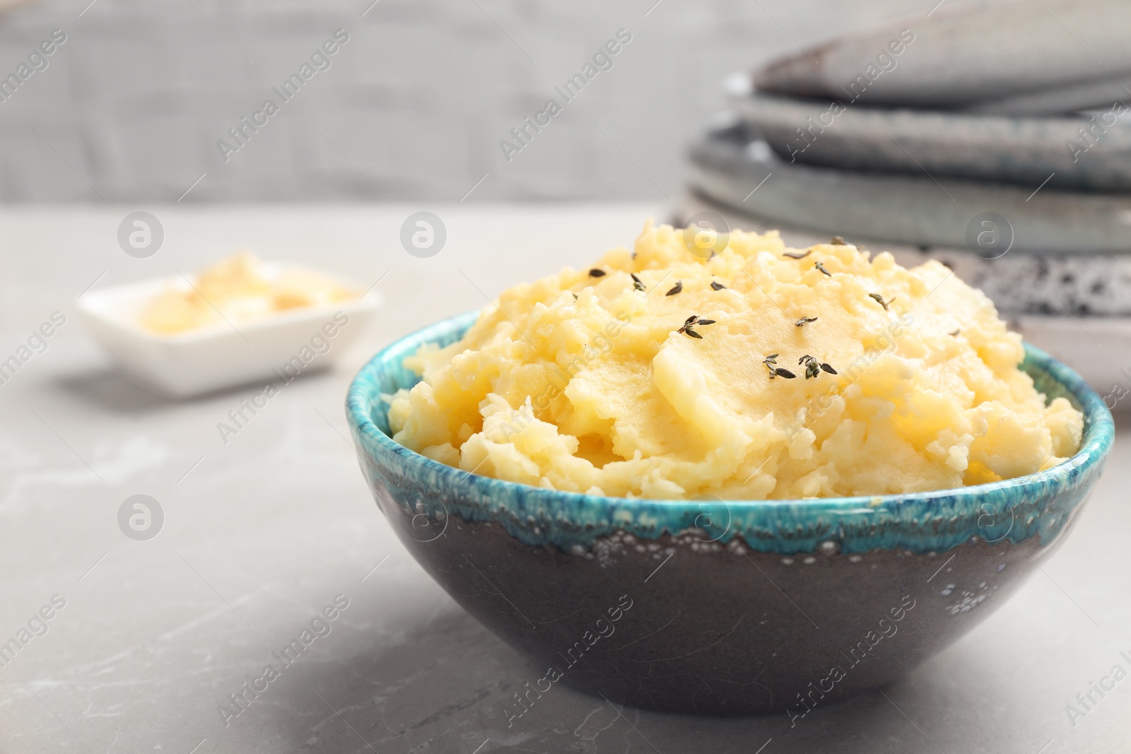 Photo of Bowl with tasty mashed potato on gray table