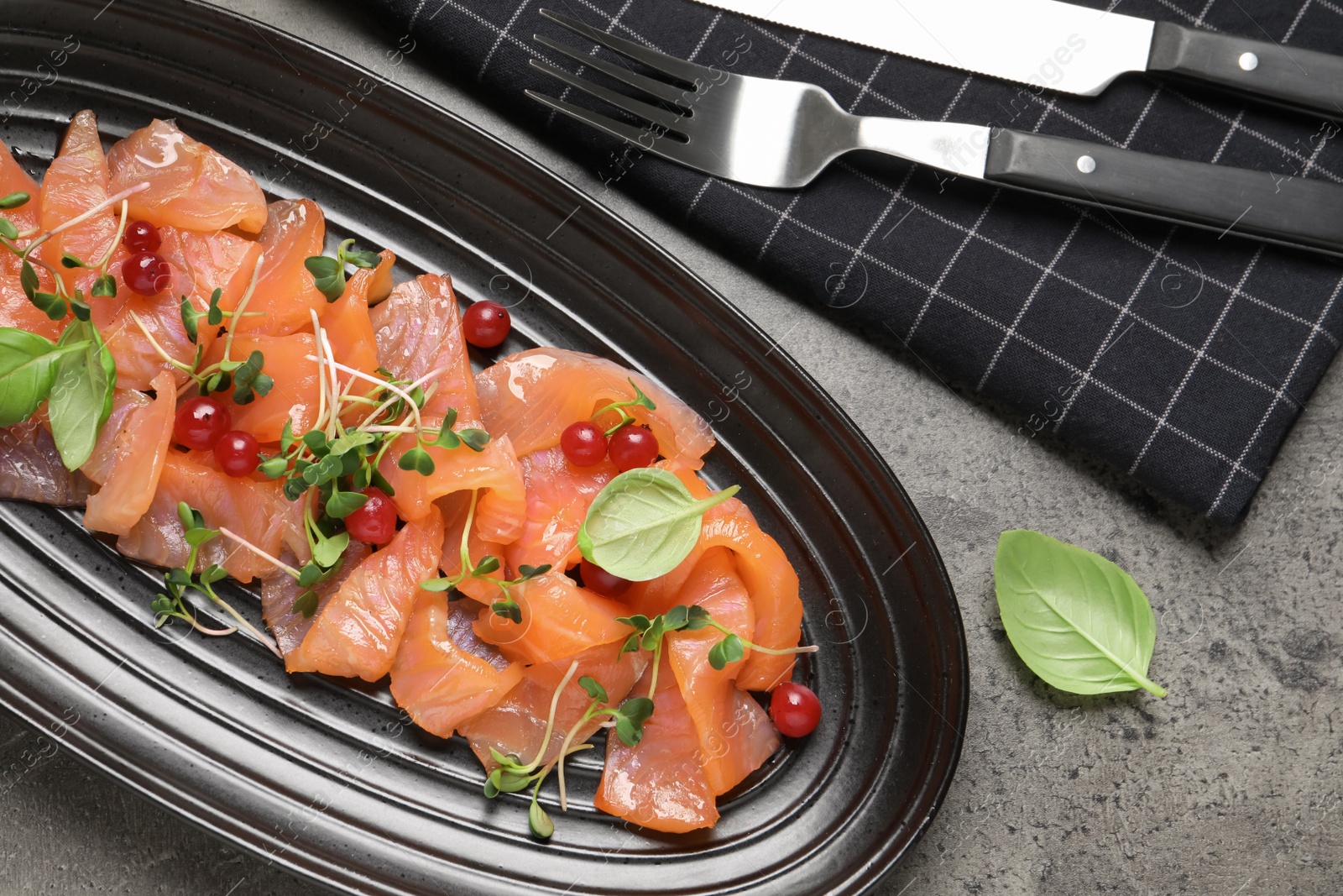 Photo of Delicious salmon carpaccio served on grey table, flat lay